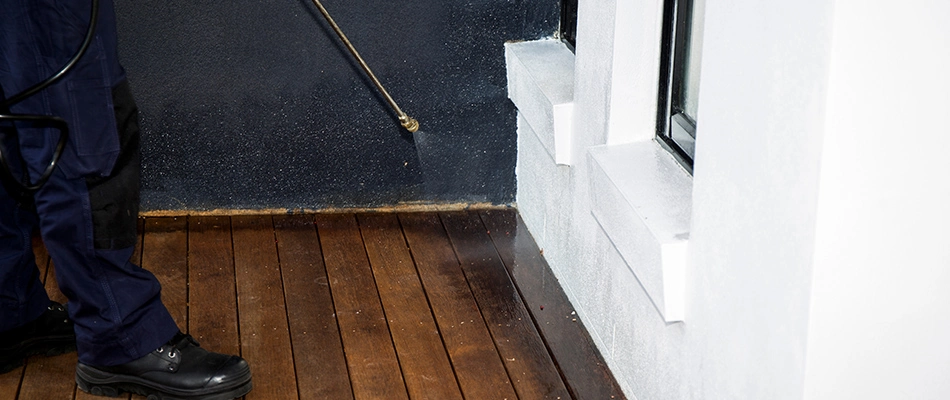 Technician spraying perimeter pest control treatment to home in Howard, WI.