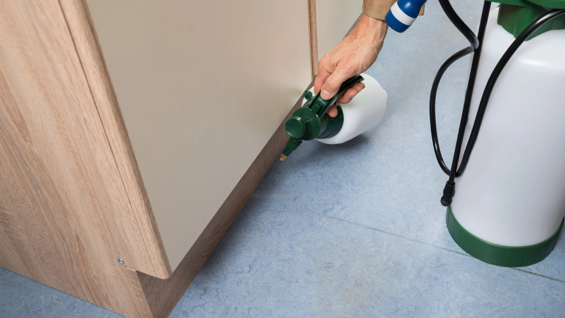 Interior pest control treatment being applied under cabinets in Escanaba, MI.