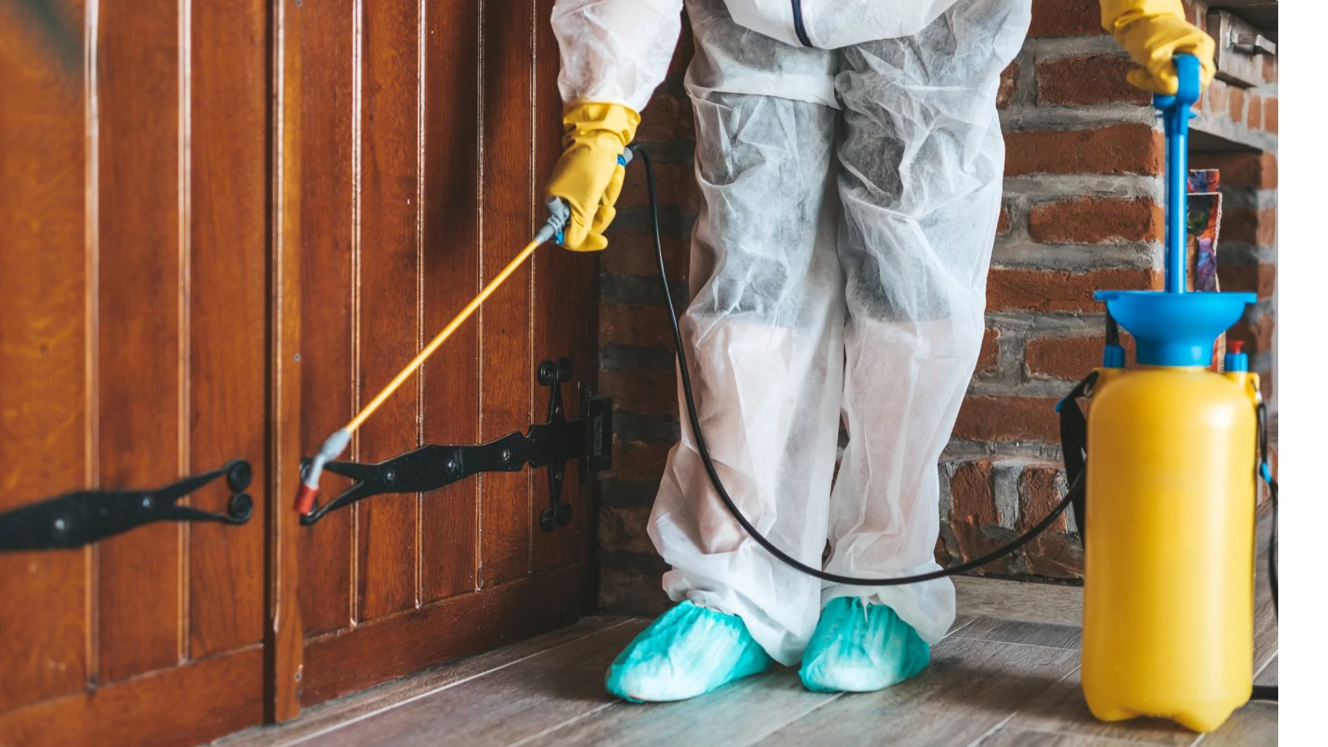 Professional applying perimeter pest control treatment near door in Kingsford, MI.