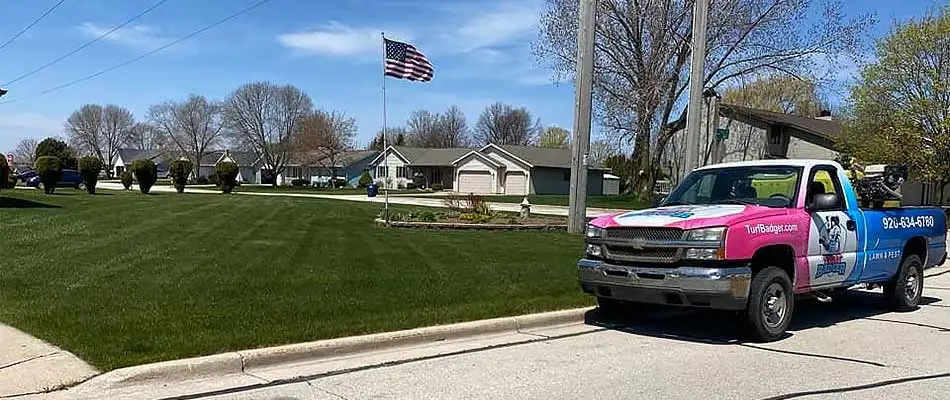 Turf Badger lawn care service truck by a deep green lawn in Bellevue, WI.